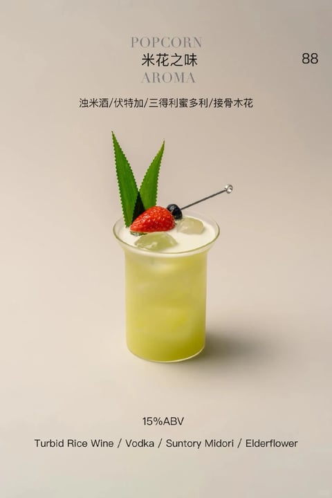 The image features a photorealistic, high-quality studio photograph of a single cocktail glass against a soft, neutral beige background, presented in a clean, minimalist composition. The main subject is a clear, slightly flared glass filled with a pale, cloudy yellow-green liquid, garnished with ice cubes, a fresh strawberry, a blueberry, and two upright green leaves, all arranged on a metal cocktail pick. The lighting is soft and diffused, coming from the front-left, creating gentle highlights on the glass rim and liquid surface while casting subtle shadows to the right, enhancing the drink's translucent, refreshing quality. Visible text in both Chinese and English is centered at the top and bottom; at the top, "POPCORN" in a light serif font sits above the Chinese characters "米花之味" and "AROMA" below, with ingredients listed underneath: "浊米酒/伏特加/三得利蜜多利/接骨木花". At the bottom, "15%ABV" appears above the English ingredients: "Turbid Rice Wine / Vodka / Suntory Midori / Elderflower". The price "88" is placed in the top right corner. The overall color palette is muted and natural, dominated by soft greens, warm reds from the strawberry, and neutral tones, with low contrast and a slightly cool color temperature. Textures are rendered with realistic detail, from the condensation-like surface of the glass to the porous, matte leaves and the glossy berry skins. The composition is balanced and centered, with ample negative space, emphasizing the cocktail as the focal point. The mood is serene, sophisticated, and inviting, with a clean, modern aesthetic suitable for a style reference.