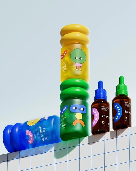 The image presents a studio-style product photography composition featuring a collection of children's nutritional supplement bottles and droppers, arranged in a dynamic, gravity-defying stack and staggered line on a white grid-patterned surface against a pale blue backdrop. The main subjects are four primary containers: a large, horizontally-oriented blue bottle lying on its side to the left, a vertically stacked pair of large bottles (yellow on top, green below) in the center, and two smaller brown glass dropper bottles standing upright to the right. The visual aesthetic is a clean, modern, and playful 3D render with a smooth, almost plasticine or vinyl-toy finish, characterized by soft rounded edges and a lack of complex surface textures. The color language is vibrant and saturated, dominated by primary and secondary colors—canary yellow, emerald green, royal blue, and magenta—set against the neutral white and soft blue, creating high contrast and a cheerful, energetic mood. Lighting is soft and diffused, coming from the upper left, casting gentle, elongated shadows to the right and below the objects, enhancing their three-dimensional form without harshness. The material feel is uniformly smooth and matte to semi-gloss, with the brown dropper bottles exhibiting a realistic amber glass quality and reflective highlights. Compositionally, the arrangement uses diagonal lines and varying heights to create visual rhythm and depth, with the stacked central bottles acting as a vertical anchor. Shape language is distinctly organic and rounded, with bottle forms featuring bulbous, ribbed, or spherical elements that echo the simplistic cartoon characters illustrated on their labels. Visible text is integrated into the product labels: the brand name 'MUNAP' appears in a stylized, playful font on the pink circular logos of the blue and yellow bottles, and on the dropper bottles. Product names and details are clearly legible in a clean sans-serif font, including 'Vitamina D 105g' on the blue bottle, 'Ómega 3 105g' on the yellow bottle, 'Vitamina' (likely Vitamin C or D) on the blue-capped dropper, and 'Ferro' (Iron) on the green-capped dropper. The language is Portuguese, indicated by words like 'SUPLEMENTO ALIMENTAR EM GOTAS' (food supplement in drops) and 'GOMÉTICAS' (gummies). The overall atmosphere is friendly, approachable, and health-focused, designed to appeal to parents seeking child-friendly wellness products.