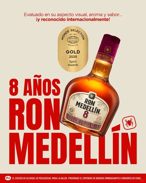 This is a promotional advertisement for Ron Medellín 8 Años rum, featuring a centered, slightly angled bottle of the dark amber liquid as the primary subject. The composition is clean and graphic, with the bottle set against a plain, off-white or light beige background. Dominant visual elements include the bottle itself, a large gold award seal, and bold red typography. The visual aesthetic is a polished, commercial photorealistic style with illustrative graphic elements, rendered to highlight the product's premium quality. The color language is defined by a high-contrast palette: the warm, rich amber and deep brown tones of the rum bottle, the gleaming metallic gold of the award seal, and the vibrant, saturated red of the large text and border, all set against the neutral background for maximum pop. Lighting is directional and studio-quality, coming from the upper left to create bright, specular highlights on the glass bottle's shoulder and neck, enhancing its three-dimensional form and glossy surface, while casting a soft, defined shadow to the lower right. Texture and material feel are highly detailed, emphasizing the smooth, reflective glass of the bottle, the textured paper of its label, the metallic foil of the award seal, and the matte finish of the typography. The composition uses a balanced, hierarchical layout with the bottle as the focal point, flanked by the gold seal above and large text below, creating a strong vertical axis and clear visual flow. Shape language combines the organic curves of the bottle with the rigid, geometric blocks of the sans-serif text and the circular seal. The mood and atmosphere convey a sense of established quality, award-winning prestige, and bold confidence, with a high-energy feel driven by the vibrant red and celebratory gold accents.