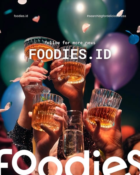 The image is a photorealistic, celebratory scene focused on the hands of multiple individuals toasting with glasses of amber-colored liquid, likely whiskey or cocktails, against a dark, festive backdrop. The composition is centered on the clustered hands and glasses, creating a sense of unity and shared joy, with a shallow depth of field that blurs the background elements—colorful balloons in shades of teal, purple, and blue, and falling confetti—while keeping the hands and glassware in sharp focus. The lighting is dramatic and moody, with a strong, warm directional source from the upper left creating high contrast: it illuminates the golden liquid in the glasses, highlights the textures of the glassware and skin, and casts deep shadows, enhancing the three-dimensional feel and intimate, party atmosphere. The color palette is rich and saturated, dominated by warm amber and gold tones from the drinks, contrasted against cool, deep teals and purples in the blurred background, with pops of bright confetti adding festive energy. Text is prominently integrated as a graphic overlay: the words 'FOODIES.ID' appear in large, bold, white, sans-serif capital letters across the center, partially obscuring the glasses; above it, 'Follow for more news' in smaller white text; 'foodies.id' in the top left; and the hashtag '#searchingfordeliciousness' in the top right. A large, cropped white 'FOODIES' text anchors the bottom edge. The overall mood is energetic, sophisticated, and celebratory, with tactile details like the condensation on the glasses, the sparkle of rings on fingers, and the glittery fabric of a sleeve adding material richness.