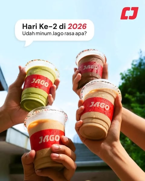 This is a vibrant, photorealistic promotional image featuring four hands raised against a bright sky, each holding a clear plastic cup of Jago-brand iced beverage. The composition is dynamic, using a low-angle perspective to frame the hands and drinks prominently, creating a sense of cheerful celebration and shared enjoyment. The cups are filled with distinct, colorful drinks—a green matcha latte, a rich brown chocolate or coffee drink, and two lighter beige or caramel-colored beverages—each wrapped in a bold red sleeve with the white 'JAGO' logo. The scene is set outdoors, with soft-focus greenery and a building structure in the background, suggesting a casual, daytime social setting. The text in the upper portion reads 'Hari Ke-2 di 2026' (Day 2 in 2026) and 'Udah minum Jago rasa apa?' (What Jago flavor have you had?), rendered in a clean, modern sans-serif font, with '2026' highlighted in red to emphasize the new year context. A red 'CJ' logo appears in the top-right corner. The lighting is bright, natural, and diffuse, casting soft shadows and creating crisp highlights on the condensation-beaded cups, enhancing the refreshing, chilled quality of the drinks. The color palette is dominated by the vibrant red of the branding, the natural greens and browns of the beverages, and the cool blues of the sky, resulting in a high-contrast, saturated, and inviting visual. The overall mood is energetic, youthful, and optimistic, conveying a sense of community and the simple pleasure of sharing a drink.