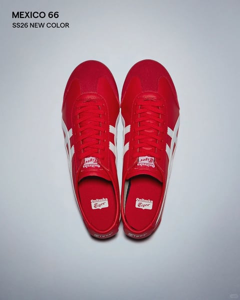 This image presents a photorealistic, top-down studio shot of a pair of vibrant red Onitsuka Tiger Mexico 66 sneakers, centered against a plain, light grey background. The composition is symmetrical, with the shoes positioned side-by-side, toes pointing upward, creating a clean, product-focused layout. The dominant color is a saturated, warm red, contrasted sharply by crisp white detailing on the signature side stripes and branding. The visual aesthetic is clean and commercial, rendered with soft, diffused lighting that minimizes harsh shadows and evenly illuminates the textures. The material feel is clearly distinguishable: the upper combines smooth, matte leather panels on the toe cap and lace area with a subtle, woven nylon fabric on the main body, while the white side stripes appear to be made of a slightly textured leather. The laces are flat and red, neatly tied. Text is a key element: at the top left, bold black sans-serif text reads "MEXICO 66" with "SS26 NEW COLOR" beneath it, identifying the model and season. The red fabric tongue label features the "Onitsuka Tiger" logo in white script, oriented vertically. Inside the shoe, the red insole displays the same "Onitsuka Tiger" logo in a white rectangular patch. The overall mood is bold, energetic, and retro-inspired, conveying a sense of classic athletic style with a fresh, high-contrast colorway. The shape language is a mix of organic curves (the toe box, heel) and clean geometric lines (the side stripes), with sharp, precise edges on the branding and sole.