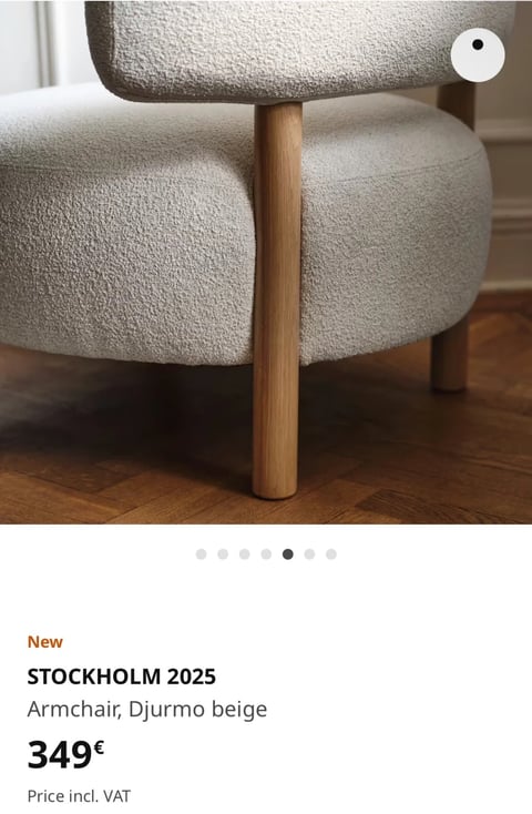 The image is a close-up, photorealistic photograph focusing on the lower section of a modern armchair, showcasing its seat cushion, wooden leg, and a portion of the backrest, set against a warm, wooden floor. The composition is tightly cropped, emphasizing the chair's materials and construction, with a shallow depth of field that softly blurs the background. Visible text in the lower section includes a bold orange 'New' label, the product name 'STOCKHOLM 2025' in large black sans-serif font, followed by 'Armchair, Djurmo beige' in smaller black text, the price '349€' in large bold black numerals, and 'Price incl. VAT' in smaller black text below, all in English, serving as product information. The visual aesthetic is clean, modern, and minimalist, emphasizing high-quality material rendering. The color language is dominated by a warm, neutral palette: the chair's upholstery is a soft, textured beige ('Djurmo beige'), complemented by the warm, medium-brown oak of the turned leg and the rich, honey-toned herringbone wooden floor, creating a cohesive, earthy, and inviting feel with moderate saturation and gentle contrast. The lighting is soft, directional, and appears to come from the upper left, casting gentle, diffused shadows that highlight the tactile texture of the boucle fabric and the smooth grain of the wood, conveying a calm, serene, and sophisticated mood. Texture and material feel are central: the upholstery has a pronounced, nubby boucle or teddy fabric texture, offering a soft, plush, and inviting tactile impression, while the wooden leg is smooth, solid, and features a visible, linear grain. Compositionally, the image uses a dynamic diagonal line created by the chair leg to lead the eye, with the upholstered sections occupying the upper two-thirds and the informational text anchored in the clean white space below. Shape language contrasts organic, rounded forms in the cushioned seat and backrest with the straight, geometric cylinder of the leg and the angular pattern of the floor. The overall mood and atmosphere are one of understated luxury, comfort, and Scandinavian-inspired simplicity, with a low-energy, tranquil, and tactile visual weight.