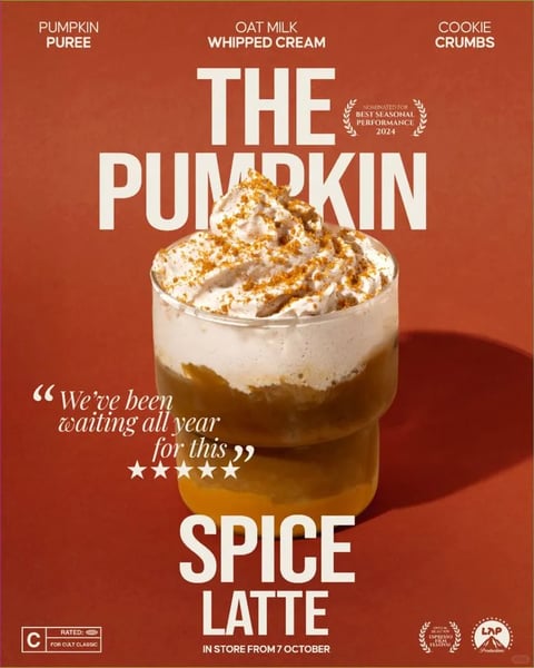 The image is a promotional advertisement with a film poster aesthetic, presented as a cohesive visual unit. The main subject is a 'Pumpkin Spice Latte' served in a clear, stacked glass, centered against a flat, burnt sienna background. The composition is vertically symmetrical, framing the drink with large, bold text above and below, creating a balanced, poster-like arrangement with moderate depth achieved through the cast shadow of the glass. The visual style is photorealistic yet highly stylized, resembling a high-end commercial food photograph with a cinematic, retro-inspired layout. The color palette is warm and autumnal, dominated by the burnt sienna background, complemented by the orange-brown of the pumpkin puree layer, the creamy off-white of the oat milk whipped cream, and the golden-brown cookie crumb topping, with deep amber shadows. The lighting is directional from the upper left, casting a sharp, defined shadow to the lower right, creating high contrast and highlighting the textures of the whipped cream and crumbs. Visible text is abundant and integral to the design, rendered in a bold, condensed, sans-serif white font. At the top, smaller text lists ingredients: 'PUMPKIN PUREE', 'OAT MILK WHIPPED CREAM', 'COOKIE CRUMBS'. The main title 'THE PUMPKIN' dominates the upper half, partially obscured by the drink's topping, with 'SPICE LATTE' in large letters below. A laurel wreath icon reads 'NOMINATED FOR BEST SEASONAL PERFORMANCE 2024'. A quote in script font states, '“We've been waiting all year for this”' accompanied by a five-star rating. The bottom includes a 'RATED C FOR CULT CLASSIC' box, festival laurels, and the text 'IN STORE FROM 7 OCTOBER'. The texture and material rendering emphasize the frothy, aerated quality of the whipped cream, the granular crunch of the cookie crumbs, and the smooth, layered liquids in the glass. The overall mood is nostalgic, inviting, and humorously dramatic, mimicking a movie release poster to create a sense of seasonal anticipation and cult-favorite status.
