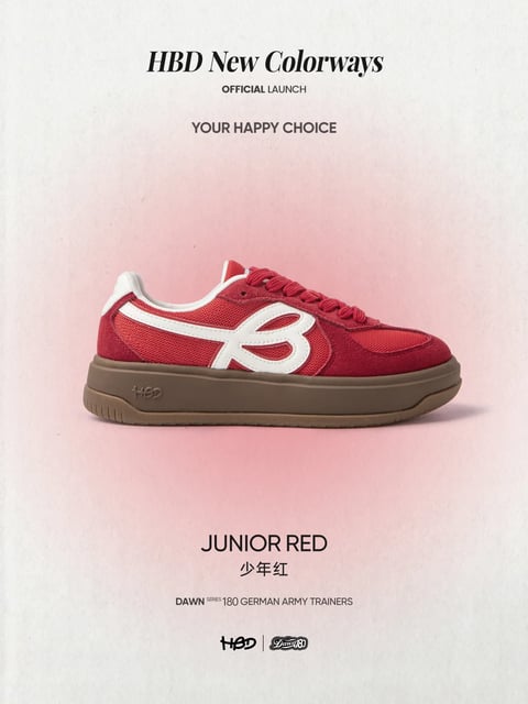 This image presents a clean, product-focused composition centered on a single low-top sneaker, the 'JUNIOR RED' model, against a softly textured, gradient background transitioning from pale cream at the edges to a muted rose-pink in the center. The sneaker is the clear main subject, rendered in a photorealistic style with meticulous detail. It features a vibrant, saturated red upper combining breathable mesh and suede-like panels, accented by a bold, off-white leather stripe forming a stylized 'B' logo. The midsole is a thick, brown gum rubber unit embossed with 'HBD', providing a warm, earthy contrast. The lighting is soft and diffused, appearing to come from the front and slightly above, casting gentle shadows that define the shoe's form without harsh edges, emphasizing its textures. The composition is minimalist and centered, with ample negative space, creating a premium, focused mood. Visible text includes 'HBD New Colorways' in a bold serif font at the top, followed by 'OFFICIAL LAUNCH' and 'YOUR HAPPY CHOICE' in sans-serif; below the shoe, 'JUNIOR RED' and its Chinese translation '少年红' are prominently displayed, with 'DAWN SERIES 180 GERMAN ARMY TRAINERS' and the 'HBD' and 'DailyB' logos at the bottom, all serving to inform and brand the product launch.