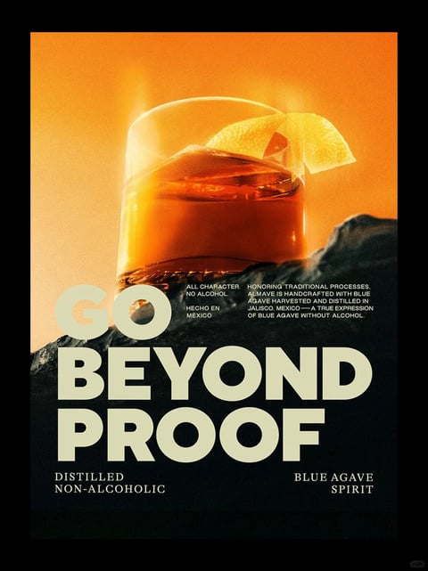 The image is a stylized, photorealistic advertisement poster featuring a close-up, low-angle shot of a rocks glass filled with an amber-colored liquid, likely a non-alcoholic spirit, garnished with a bright yellow lemon peel twist. The glass rests on a rugged, dark gray rock formation that dominates the lower foreground, with the background being a smooth, vibrant gradient of warm orange to yellow, evoking a sunset or warm light. The composition is centered and vertically oriented, with the glass and rock creating a strong focal point against the luminous backdrop. Visible text is integrated into the lower half of the image: the large, bold, sans-serif headline 'GO BEYOND PROOF' in an off-white color is prominently placed over the rock, with smaller white text above it reading 'ALL CHARACTER. NO ALCOHOL.' and 'HECHO EN MÉXICO' on the left, and a descriptive paragraph on the right stating 'HONORING TRADITIONAL PROCESSES, ALMAVE IS HANDCRAFTED WITH BLUE AGAVE HARVESTED AND DISTILLED IN JALISCO, MÉXICO — A TRUE EXPRESSION OF BLUE AGAVE WITHOUT ALCOHOL.' Additional text at the bottom reads 'DISTILLED NON-ALCOHOLIC' on the left and 'BLUE AGAVE SPIRIT' on the right. The visual aesthetic is a polished, commercial photography style with high contrast and rich saturation, emphasizing a warm, inviting color palette of deep amber, golden yellow, and orange against dark, cool-toned rocks. Lighting appears to be backlit or side-lit from the left, creating a glowing halo effect on the glass and liquid, with soft highlights on the lemon peel and sharp, dramatic shadows on the rock textures. The texture contrast is pronounced, with the smooth, reflective glass and fluid liquid juxtaposed against the rough, granular surface of the stone. The mood is sophisticated, warm, and slightly dramatic, conveying a sense of premium quality and natural craftsmanship.
