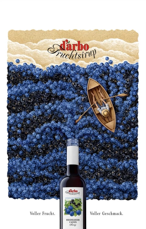 The image is a highly stylized, illustrative composition serving as an advertisement, merging a top-down landscape view with a product shot. The main visual field is a dense, textured 'sea' made entirely of blueberries and darker cassis berries, creating a rolling, wave-like surface that fills most of the frame. In the upper portion, this blueberry sea meets a stylized shoreline of torn, layered paper in beige and off-white tones, resembling sand and foam. A small, wooden rowboat with a single, relaxed figure reclining inside is positioned on the berry 'water,' viewed from above. In the lower foreground, a dark glass bottle of 'd'arbo Fruchtsirup' (fruit syrup) stands vertically, its label visible, creating a sense of depth as it appears to be in front of the illustrative scene. The visual aesthetic is a surreal photorealistic collage; the berries are rendered with photographic detail and texture, while the boat, figure, and paper shore have a crafted, illustrative quality. The color language is dominated by a rich spectrum of blues and deep purples from the berries, with high saturation and contrast against the warm, neutral beige of the shore and the dark amber of the syrup bottle. Lighting is directional from the upper left, casting soft shadows among the berries to define their spherical forms and create a dappled, undulating texture, while the boat interior is warmly lit. Texture is paramount, with the glossy, bumpy surfaces of individual berries contrasting with the smooth wood of the boat and the rough, fibrous edges of the paper shore. The composition is vertically oriented, using a forced perspective that layers the bottle, berry field, boat, and shoreline to create a whimsical, deep spatial arrangement. Shape language is organic, dominated by the countless small spheres of the berries and the curved, flowing lines of the 'waves,' contrasted by the simple geometric oval of the boat. The mood is playful, abundant, and refreshing, conveying a sense of natural richness and leisurely indulgence. Visible text includes the brand logo 'd'arbo Fruchtsirup' in a stylized red and black script at the top center, and the bottle label which reads 'd'arbo Fruchtsirup,' 'HEIDELBEER CASSIS Sirup,' and the phrases 'Voller Frucht.' and 'Voller Geschmack.' (Full Fruit. Full Flavor.) at the bottom; all text is in German, integrated as part of the product branding and advertisement message.
