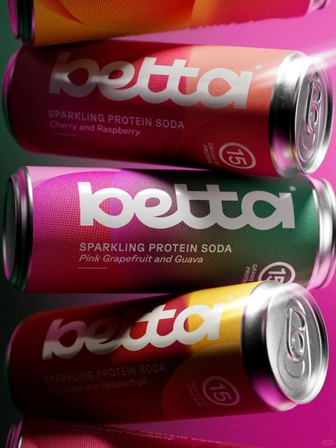 The image presents a close-up, high-angle composition of multiple aluminum beverage cans stacked diagonally, creating a dynamic, layered arrangement. The primary subject is the 'Betta' brand of sparkling protein soda, with cans featuring a sleek, modern 3D rendering style that emphasizes metallic sheen and vibrant gradients. The dominant color palette is highly saturated and contrasting, featuring deep magentas, vibrant pinks, rich greens, and warm ambers, with the silver aluminum of the can tops and bottoms providing a cool metallic counterpoint. Lighting is directional and crisp, coming from the upper left, casting sharp highlights on the curved can surfaces and creating soft, defined shadows that enhance the three-dimensional form and the glossy, reflective quality of the printed labels. Text is prominently integrated into the design; the brand name 'betta' appears in a large, bold, lowercase sans-serif font in white, centrally placed on each can. Below this, smaller text specifies 'SPARKLING PROTEIN SODA' and the flavor combination, such as 'Cherry and Raspberry', 'Pink Grapefruit and Guava', and 'Pineapple and Passionfruit'. A circular badge indicating '15 GRAMS OF PROTEIN' is also visible. The texture is smooth and tactile, with the fine grain of the printed metal and the polished, reflective finish of the aluminum lids clearly rendered. The composition uses a shallow depth of field, with the central can in sharp focus while the cans above and below soften slightly, drawing the eye to the middle of the frame. The overall mood is energetic, contemporary, and appetizing, conveying a sense of vibrant refreshment and modern wellness through its bold color blocking, clean typography, and polished, photorealistic rendering.