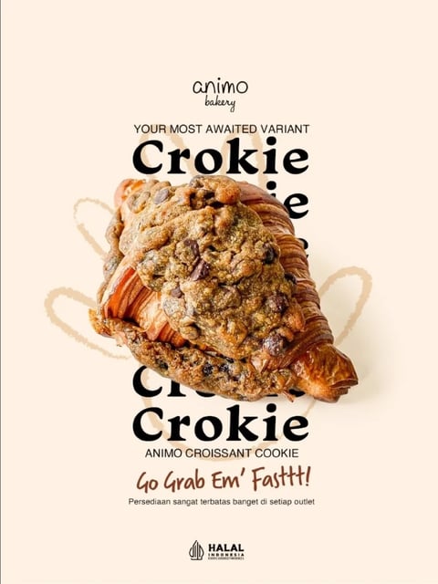 This is a photorealistic, high-contrast promotional image for a bakery product. The composition centers on a single "Crokie" (a hybrid croissant-cookie), shot from a slightly elevated three-quarter angle to showcase its layered, flaky croissant base and the thick, textured chocolate chip cookie dough baked on top, with the pastry's golden-brown, laminated layers clearly visible on the sides and bottom. The image uses a clean, minimalist flat-lay style against a solid, soft beige background. The dominant color palette is warm and earthy, featuring the rich browns and deep chocolate tones of the pastry against the creamy, neutral backdrop, creating a cozy and appetizing mood. Lighting is soft, diffuse, and directional from the upper left, casting gentle, natural-looking shadows to the right and below the pastry, enhancing its three-dimensional form and the tactile contrast between the crisp, layered croissant and the soft, craggy cookie surface. Text is integrated as a central design element: at the top, the small, delicate script "animo bakery" sits above the phrase "YOUR MOST AWAITED VARIANT" in a clean, uppercase sans-serif font. The word "Crokie" is prominently displayed in a large, bold, black serif typeface, both behind and below the main pastry image, partially obscured by the product to create depth. Below the pastry, "ANIMO CROISSANT COOKIE" appears in a smaller sans-serif font, followed by the energetic, handwritten-style call to action "Go Grab Em' Fasttt!" in a dark brown color. A final line of smaller text in Indonesian, "Persediaan sangat terbatas banget di setiap outlet," is centered near the bottom. A small, circular "HALAL INDONESIA" certification logo is placed at the very bottom center. The overall atmosphere is inviting, modern, and premium, with a strong focus on the delicious, hybrid texture of the featured pastry.