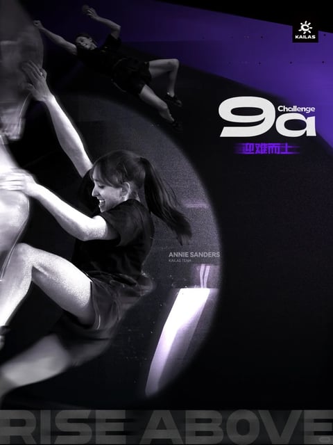 This is a high-energy promotional poster with a dominant dark, moody aesthetic, rendered in a photographic style that combines sharp focus with dynamic motion blur. The composition centers on a female climber, Annie Sanders of the KAILAS TEAM, captured mid-climb on a smooth, curving, dark surface; her body is angled dynamically, with one arm extended upward and her expression showing intense effort and exhilaration, her hair flying back. A secondary, smaller image of the same climber is positioned in the upper left, shown in a more relaxed, celebratory pose. The scene is set against a deep, dark background with a prominent, large, glowing purple oval shape that frames the climber and text, creating a sense of depth and spotlighting. The color language is limited and dramatic, primarily relying on a grayscale range for the climber and background, punctuated by the vibrant, saturated purple of the oval and text elements, which creates high contrast. The lighting is directional and harsh, seemingly from a spotlight source, casting sharp highlights on the climber's skin and the climbing surface while plunging other areas into deep shadow, enhancing the dramatic and intense mood. Visible text includes a large, stylized white '9a' with 'Challenge' in smaller white text above it in the upper right, accompanied by Chinese characters '迎难而上' (meaning 'rise to the challenge') below it in purple; the name 'ANNIE SANDERS' and 'KAILAS TEAM' appear in small white sans-serif font near the center; the KAILAS logo is in the top right corner; and the phrase 'RISE ABOVE' is embossed in large, dark, low-contrast letters across the very bottom. The texture is a mix of the smooth, matte finish of the climbing wall and the slightly grainy, dynamic blur of the climber's movement, suggesting a fast-paced action shot. The overall mood is one of intense physical challenge, aspiration, and high-energy achievement.