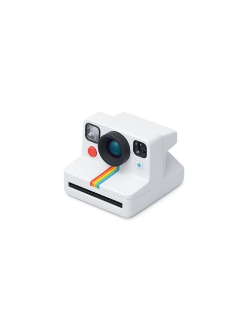 The image presents a studio-style product shot of a white instant camera, positioned at a three-quarter angle against a plain white background, serving as the clear focal point. The camera features a classic Polaroid-inspired design with a large, prominent black lens at the center, a small square flash unit to its upper left, and a bright orange-red shutter button below it. A thin, diagonal rainbow stripe in red, orange, yellow, green, and blue runs from below the lens towards the front film slot, adding a vibrant pop of color. The camera body has a smooth, matte white plastic texture with subtle, clean geometric lines and rounded edges. To the right of the lens, a small, square viewfinder window and a tiny white button with a light blue plus sign are visible. The lighting is soft and diffused, coming from the upper left, creating gentle shadows that define the camera's form and give it a three-dimensional feel without harsh contrasts. There is no visible text or branding on the camera body itself. The composition is clean and centered, emphasizing the object's design and color accents against the neutral backdrop, conveying a playful yet minimalist aesthetic.