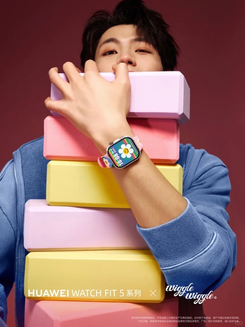 The image features a young person with dark, textured hair and light makeup, holding a stack of five soft, matte-textured, rectangular foam blocks in alternating pastel colors (purple, pink, yellow, pink, yellow) up to their face, with their right arm bent to display a smartwatch on their wrist. The person wears a blue zip-up hoodie, and the background is a solid, deep maroon. The watch has a rectangular face with a glossy black bezel and a pink, flexible strap printed with small, colorful floral patterns. The watch face displays a vibrant, colorful graphic of a white daisy on a rainbow-striped background, with the digital time '10:08' in large white numerals and 'HUAWEI' in smaller text. Visible text includes 'HUAWEI WATCH FIT 5 系列' in white, sans-serif font on the lower yellow block, 'wiggle wiggle' in a stylized, white script on the lower right, and small, white disclaimer text at the very bottom. The overall composition is playful and stylized, with a focus on the watch as a fashion accessory, highlighted by the person's prominent hand and arm position, the colorful blocks, and the vibrant watch face.