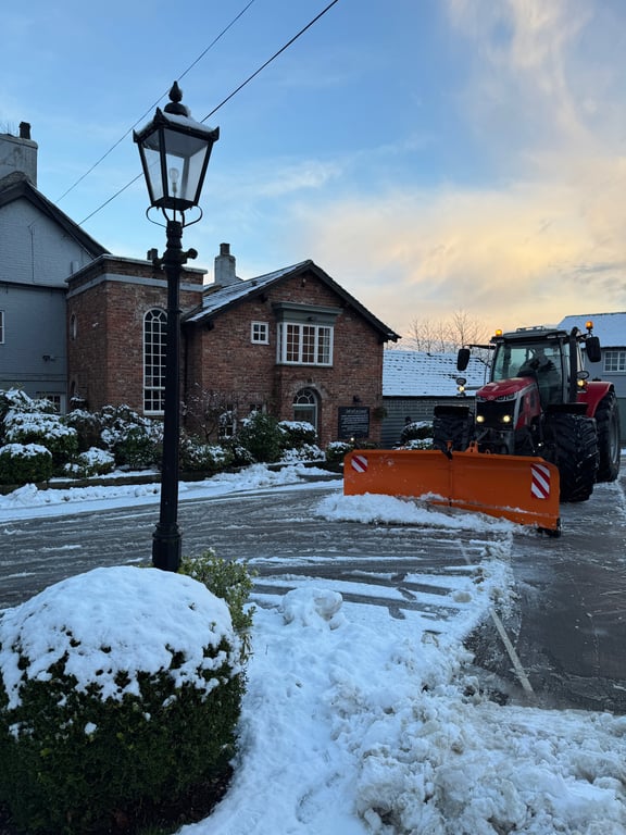 Tractor with snow plow clearing snow at a local pub