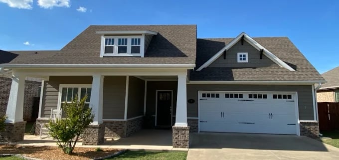 This is an image from Mancini Custom Painting, located in Oklahoma. The photo shows a freshly painted modern suburban home with gray siding, white trim, and a two-car garage.