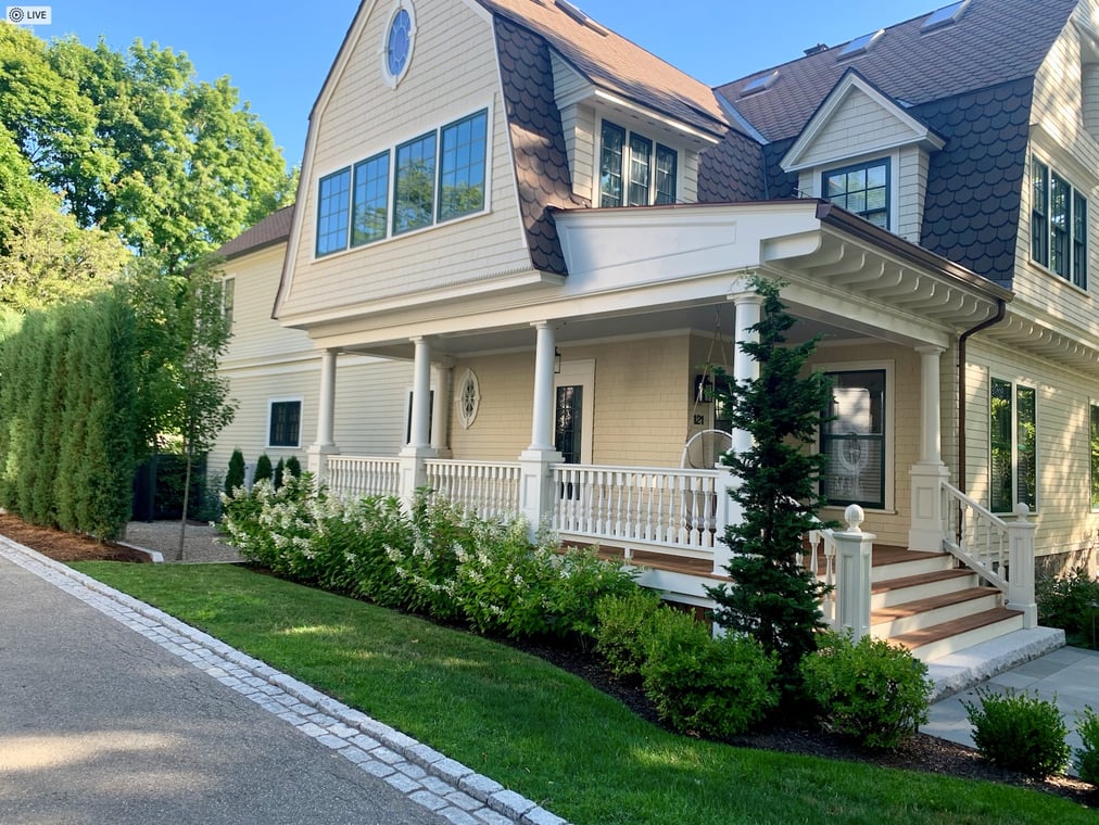 This is an image from Big Dog Painting, located in Massachusetts. The photo shows a beautifully painted beige home with white trim and a large front porch, highlighting the company’s expertise in exterior residential painting.