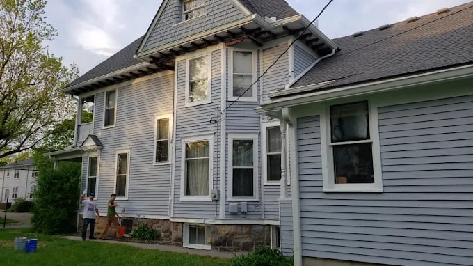 This is an image from Saline Painting company, located in Saline, MI The image is an exterior of a large two-story home with gray siding being prepped for painting by Saline Painting crew in Saline, MI.