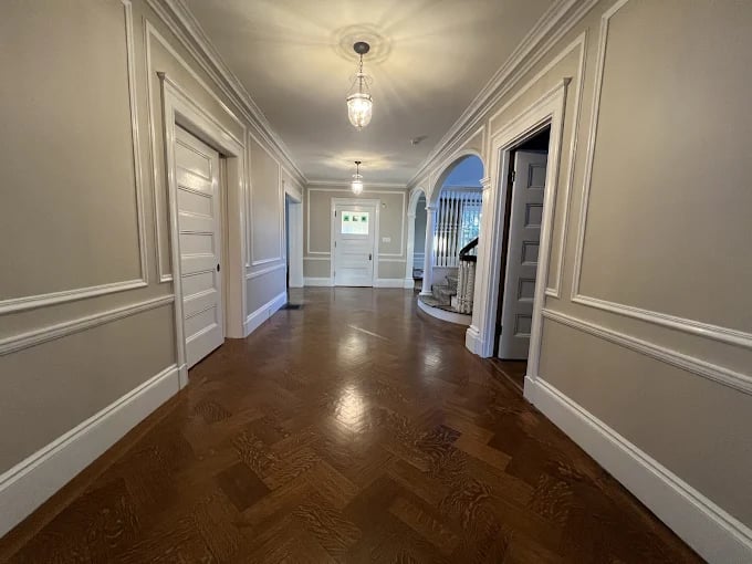 This is an image from CertaPro Painters of Newton, Massachusetts. The photo features a two-story gray house with white trim and a front porch, freshly painted for a clean and modern curb appeal.