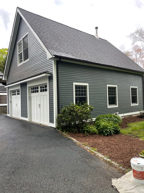 This is an image from Laperle Painting Company, located in Massachusetts. The photo shows a freshly painted gray detached garage with white trim, double carriage-style doors, and neatly landscaped surroundings.