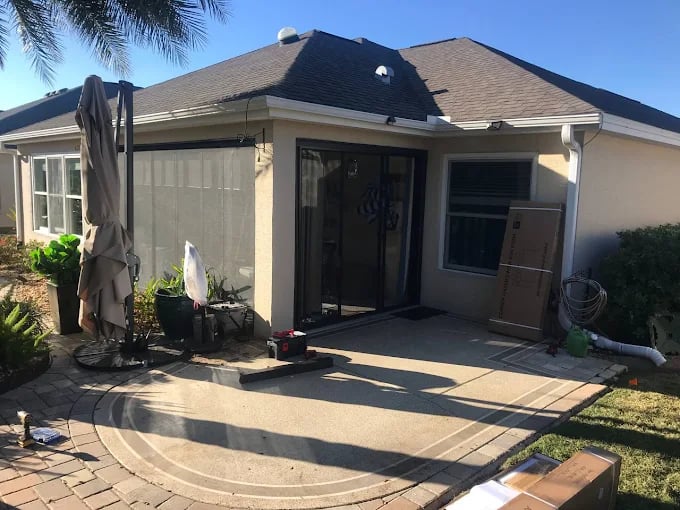 This is an image from Golden Hands Handymans company, located in Windermere, FL. The image is a backyard patio area of a residential home with paver border, outdoor umbrella, and boxed equipment prepared for handyman installation