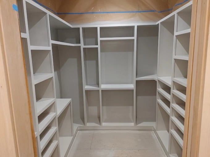 This is an image from Color Changer, LLC company, located in Hayden, ID The image is a custom-built walk-in closet with freshly painted white shelving and storage units by Color Changer LLC