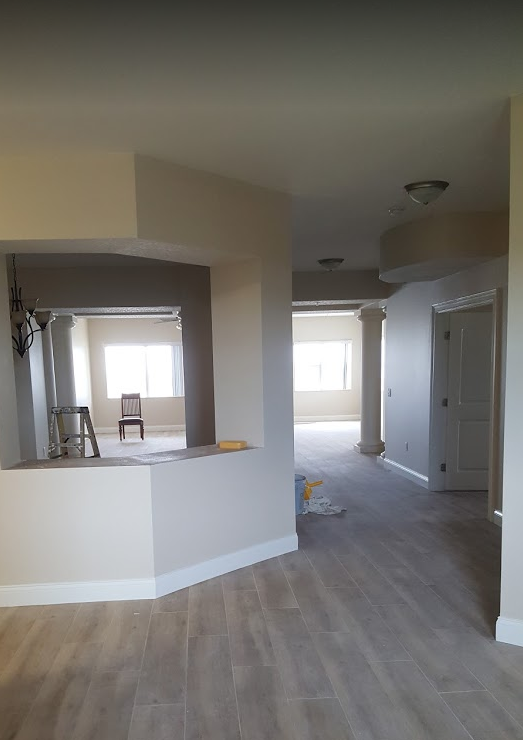 This is an image from Paint Masters Painting Contractors LLC company, located in Venice, FL. The image is a freshly painted interior of a residential home with open layout, light beige walls, white trim, and wood-look tile flooring by Paint Masters Painting Contractors LLC
