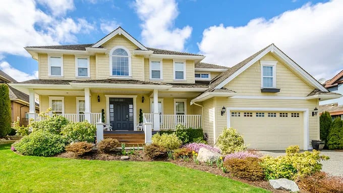 This is an image from WM Painting & More, located in Massachusetts. The photo shows a freshly painted two-story yellow home with white trim, black front door, and well-maintained landscaping.