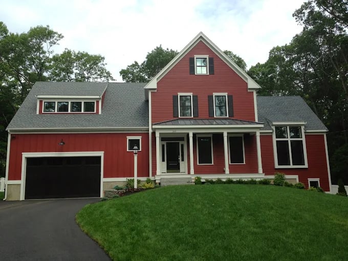 This is an image from DiNapoli Painting, located in Massachusetts. The photo shows a freshly painted two-story red home with white trim, black shutters, and a dark gray roof.
