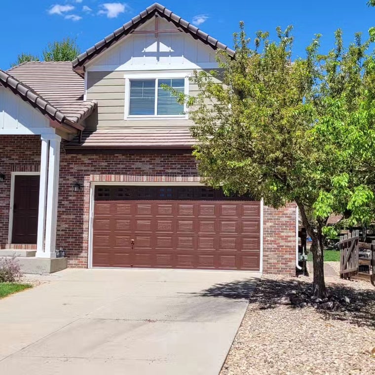 This is an image from Pro Classic Painting company, located in Aurora, CO The image is a residential home with freshly painted brown garage door, brick exterior, and light siding, completed by Pro Classic Painting