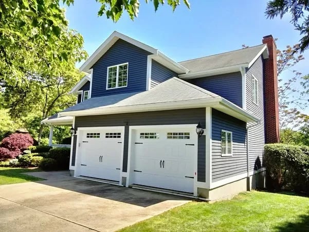 This is an image from ProTEK Painters, located in Massachusetts. It shows a bright turquoise house with yellow trim and a small covered porch, with a ProTEK Painters yard sign in front.