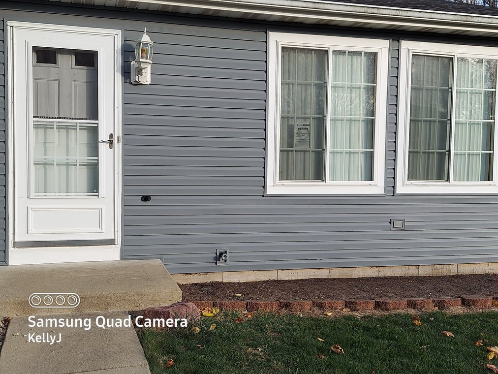 This is an image from ProLine Painting company, located in Antioch, IL The image is an exterior house siding painted in modern gray with white trim around door and windows by ProLine Painting