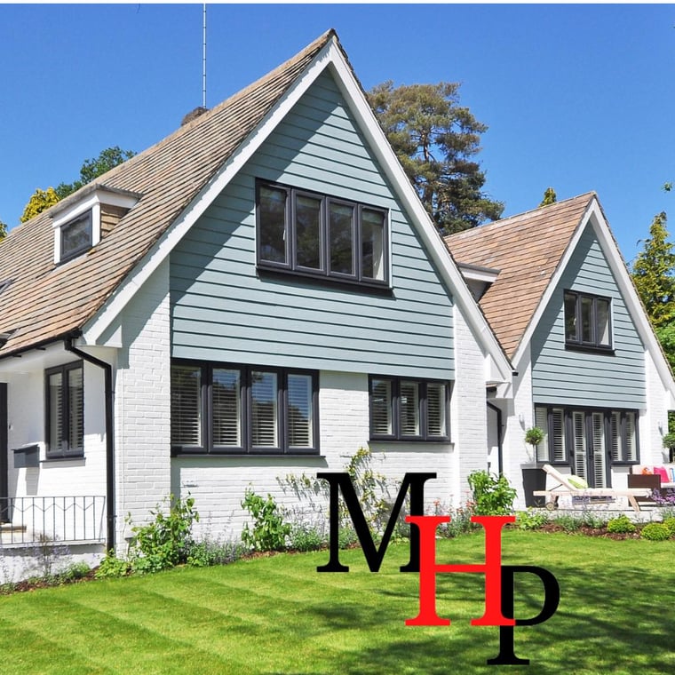 This is an image from Majestic Home Painting, showcasing a modern two-story home with light blue siding and white brick exterior. The design highlights black framed windows and a neatly maintained green lawn.