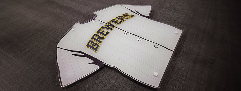 Custom clear acrylic sign shaped as a baseball jersey and printed using white ink.