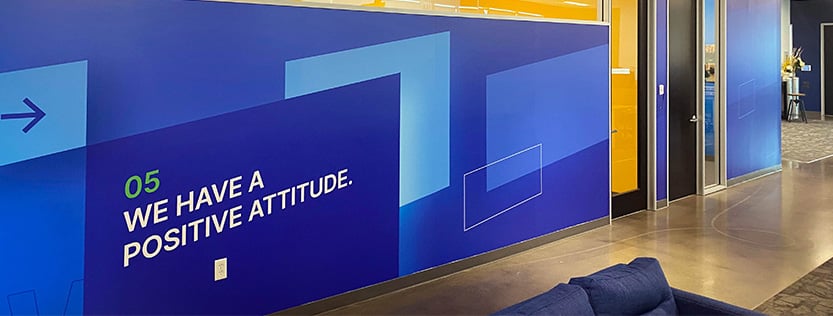 large blue geometric wall wrap for business featuring words saying "we have a positive attitude".