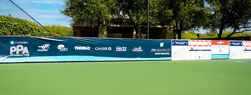 fence banner graphics for business sponsors on a pickleball court.