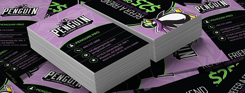 close-up of purple and black penguin air business cards in a stack and scattered around.