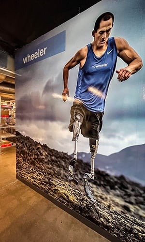 wall mural print of a man with two prosthetic legs running through rough terrain.