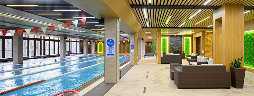 Indoor private club pool with signage on the columns.