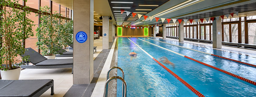 Indoor swimming pool with safety signage on the columns.