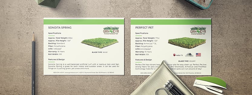 Two postcards for grn 4 evr turf company sitting on a concrete table.