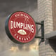 Round printed wall-mounted signage for Dumpling restaurant.