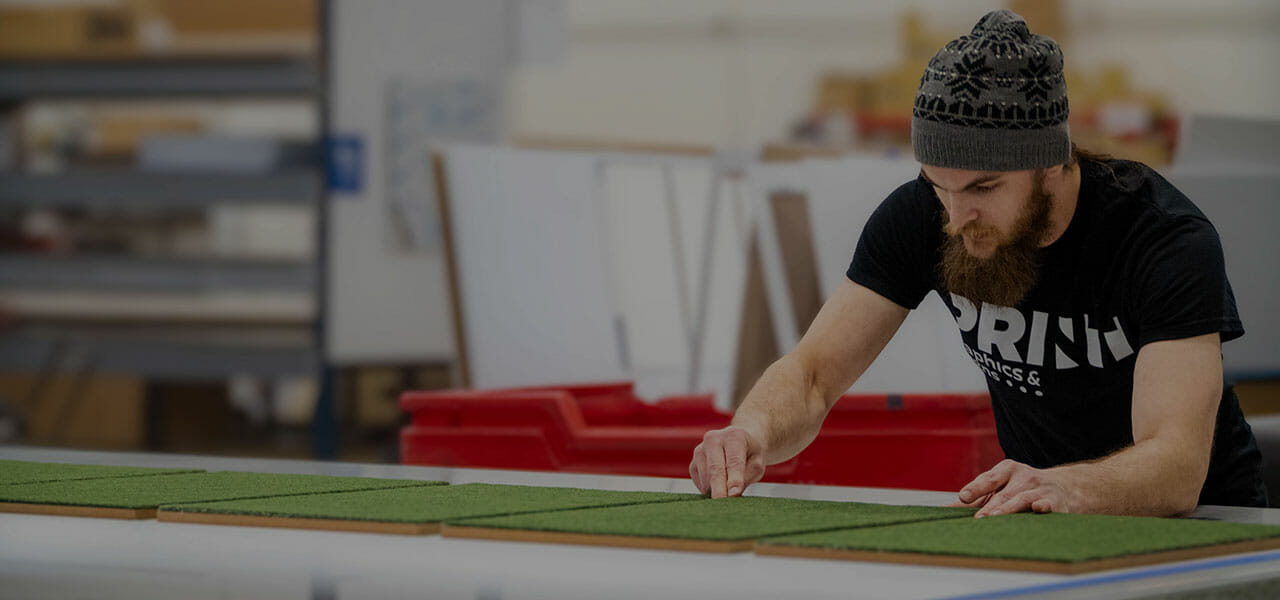 A man in a beanie working at a flatbed printer