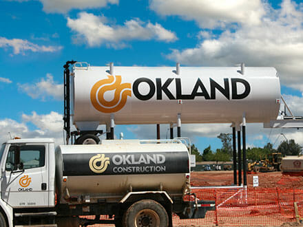 Oakland Construction Equipment logo on a vehicle and on a large tank that is up on stilts.