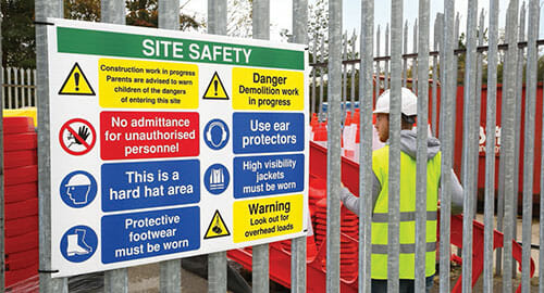 Construction site safety sign attached to a fence.