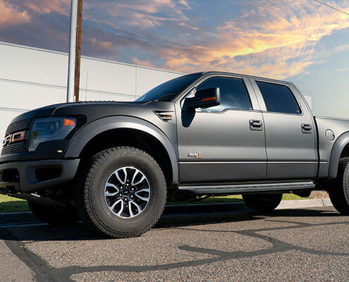 Full color change wrap in matte black with orange accents for a Ford Raptor