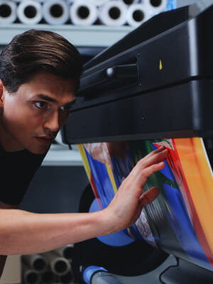 Print operator checking the quality of printed material on a latex printer.