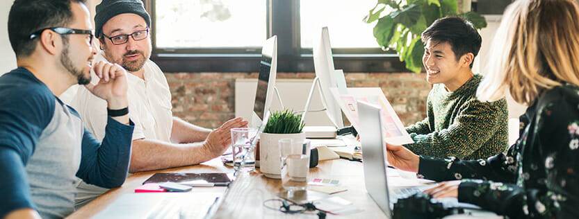 Group of people discussing work at a conference table.