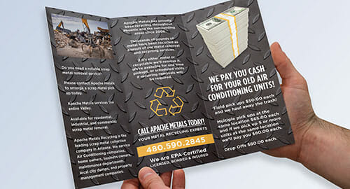 Hands holding open a trifold brochure for a metal recycling company.