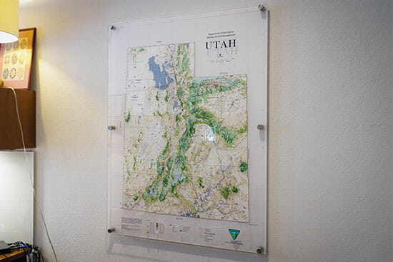 A printed map of Utah mounted behind acrylic glass on an office wall.