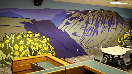 Colorful artwork of a mountain scene is installed as a wall covering.