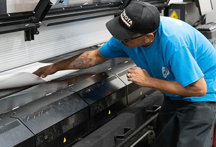 Print operator adjusting material in a roll-to-roll latex print machine.